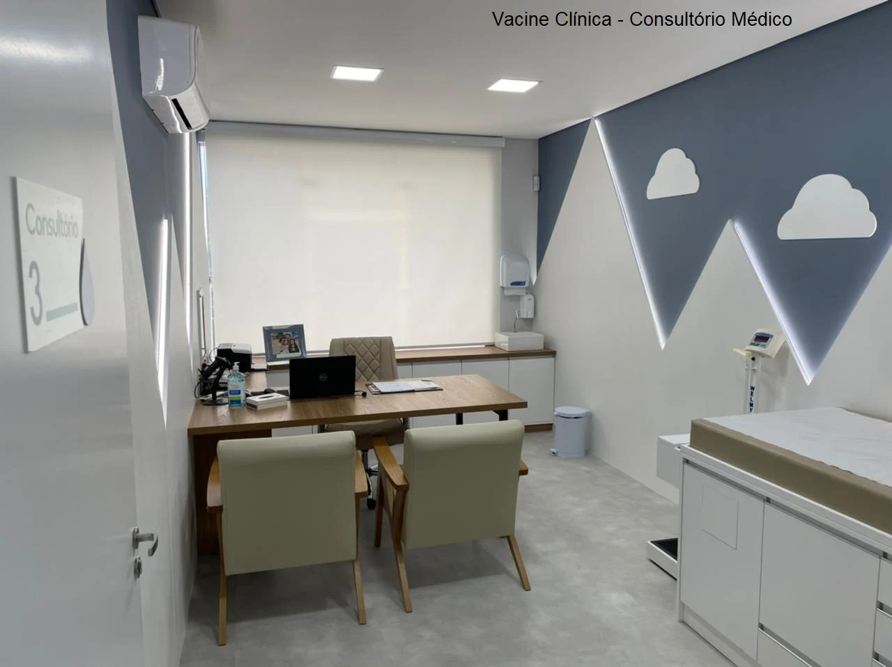 Sala de atendimento da Vacine Clínica com mesa, cadeiras e parede decorada com montanhas e nuvens